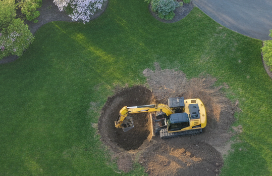 Excavator digging and grading land for a Cape Cod landscaping project