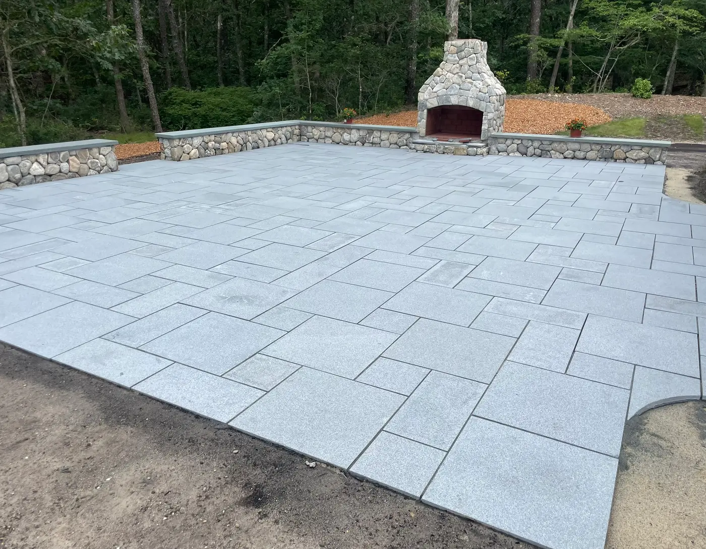Stone fireplace, seat wall, and granite paver patio built by John G. Sears & Son on Cape Cod