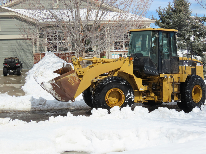 Snow plow clearing a residential driveway after a winter storm on Cape Cod